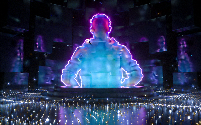 一个虚拟舞台，中央有发光的表演者轮廓，台下是无数闪烁的星光代表观众